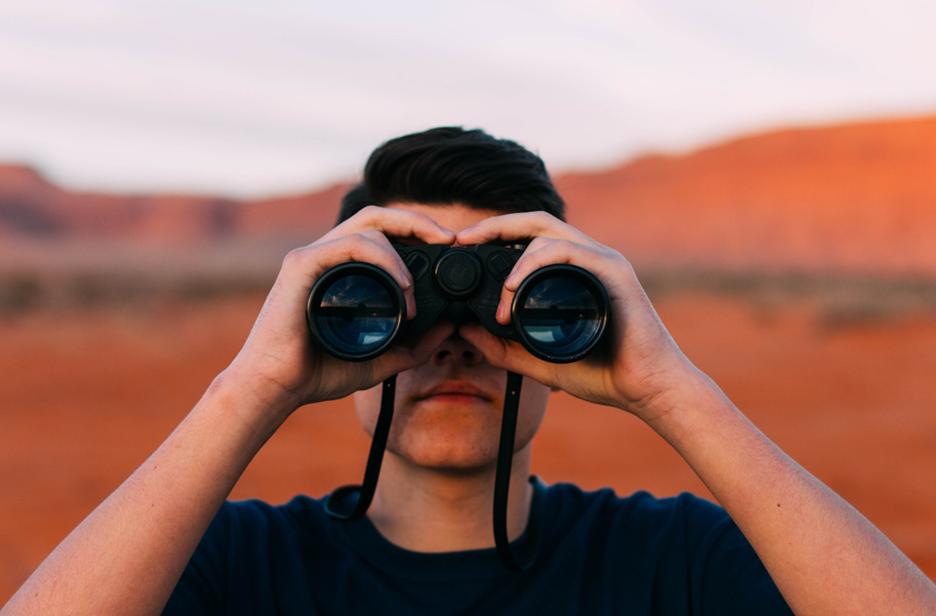 Contenet and SEO What You Need To Know. SEO Tips. Search Engine Optimization. seo. search engine optimization tips. Image of a man standing in the desert looking through binoculars.